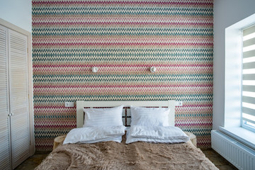 Interior of a spacious hotel bedroom with fresh linen on a big double bed. Cozy contemporary room in a modern house.