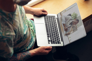 Young man getting online medical help and advice during videocall with doctor checking symtoms and explaining the drug's reciepes. Connection during self-insulation using laptop, headphones, phone.