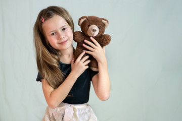 Pretty child girl playing with her teddy bear toy.