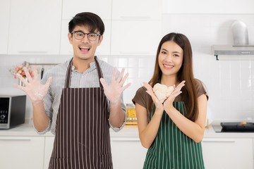 Romantic young Asian couple prepare cooking thresh flour together in white kitchen.