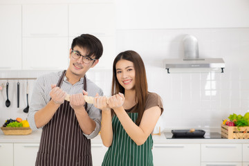 Romantic young Asian couple prepare cooking thresh flour together in white kitchen.