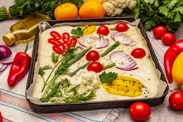 Raw garden focaccia. Fresh dough and vegetables, olive oil, greens