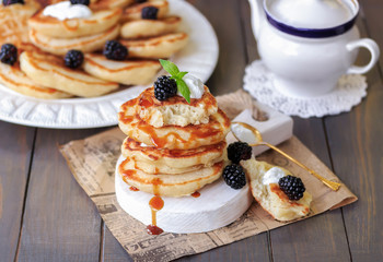 Fluffy Pancakes with blackberries, yogurt, and caramel syrup. Dark wooden background, selective focus.
