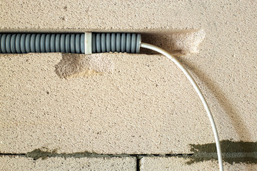 Electrical cables laid in protective corrugation installed on the ceiling and wall in a room under...
