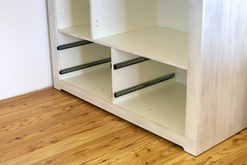 Fototapeta premium Close up of installation of wooden drawer in contemporary cupboard cabinet.