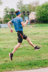 A young athlete in a blue T-shirt runs around the stadium