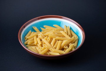 Raw penne on a black background