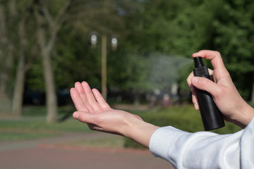 Spray antiseptic on hands close-up. Compliance with security measures. Girl in the Park. Space for text. spray freeze frame