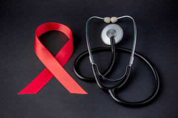 Red ribbon and stethoscope on a concrete background. 1 December World AIDS Day, HIV illness campaign