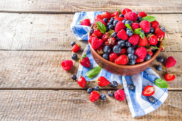 Raw Organic Assorted Various Fresh Berries with Blueberries Raspberries and Strawberries on rustic wooden background