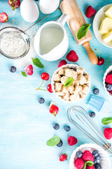 Berry cake baking recipe. Summer cooking baking background with assorted berries, baking ingredients, tools and utensils, light blue sun lighted wooden background flat lay top view copy space