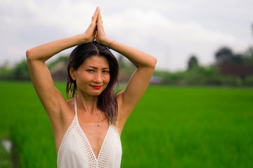 Naklejka na ściany i meble outdoors holidays portrait of attractive and happy middle aged Asian Korean woman in white dress enjoying freedom and nature at green field landscape carefree and cheerful
