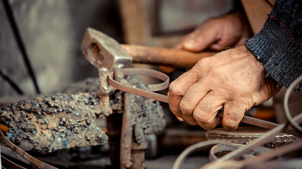 hand holding hammer with metal rod tied