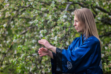 a girl practices tai Chi in a wild Apple orchard