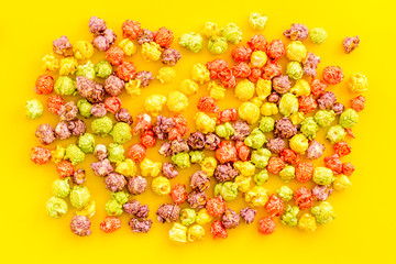 Colored popcorn on yellow background top view