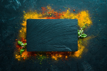 Colorful herbs and spices for cooking. Indian spices. On a black stone background. Top view.