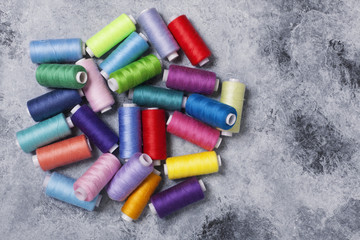 Colorful threads on bobbins, sewing set.On gray concrete background. Place for text.