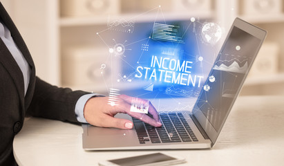 Side view of a business person working on laptop with INCOME STATEMENT inscription, modern business concept