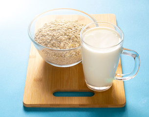 glass mug with milk and a glass bowl with oatmeal on a blue background. Healthy breakfast.