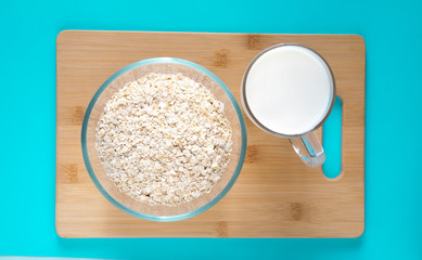 glass mug with milk and a glass bowl with oatmeal on a blue background. Healthy breakfast.
