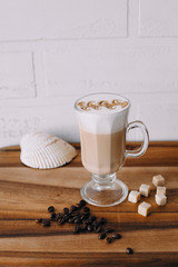Coffee in glass mug, coffee beans and sugar cubes on wooden table 