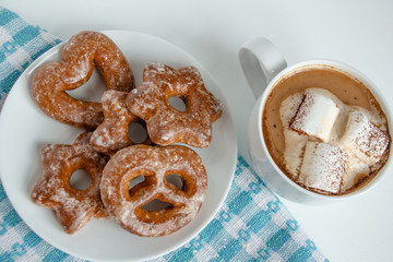 fragrant gingerbread cookies on a white plate with a cup of warm cocoa or coffee with marshmallow, sprinkled with chocolate, white background, blue napkin, delicious dessert, feeling of comfort
