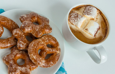 fragrant gingerbread cookies on a white plate with a cup of warm cocoa or coffee with marshmallow, sprinkled with chocolate, white background, blue napkin, delicious dessert, feeling of comfort
