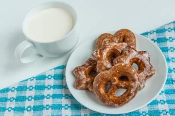 fragrant gingerbread cookies on a white plate with a cup of warm fresh milk, white background, blue napkin, delicious dessert, creating a feeling of homeliness