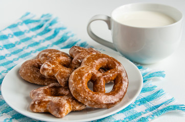 fragrant gingerbread cookies on a white plate with a cup of warm fresh milk, white background, blue napkin, delicious dessert, creating a feeling of homeliness