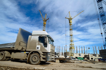 House construction. A truck carrying construction materials enters the construction site.