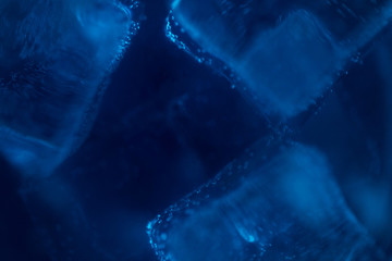 Blue sparkling water with ice cubes and bubbles macro close up