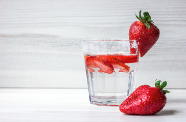 A refreshing drink of strawberries in a glass and berries on a background of light wood