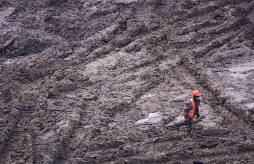 Workers in the mud of a construction site at the stage of excavation; construction of a supermarket AUCHAN