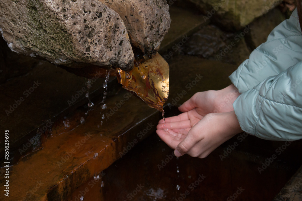 Wall mural Children’s hands draw water from the Holy Spring of Panteleimon. Hot key