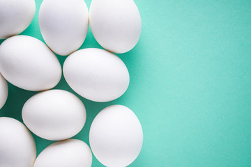 white chicken eggs on green pastel background
