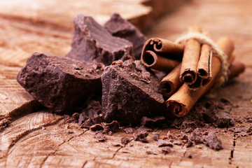Obraz na płótnie Canvas Cinnamon sticks and dark chocolate on a wooden background