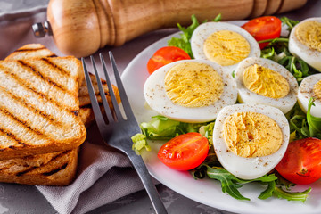 salad with boiled chicken eggs and cherry tomatoes on a stone background
