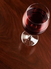glass of red wine resting on wooden background