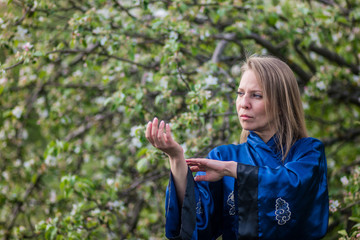 a girl practices tai chi qigong against the background of a blooming Apple tree