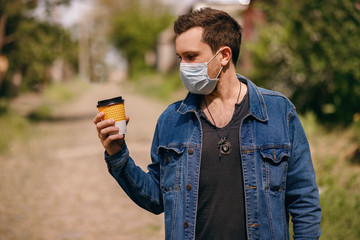 A man in a protective mask with coffee in his hand, the coronovirus interferes with a full life