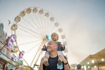 Fotobehang Amusementspark Gelukkige vader met zijn zoontje in een pretpark