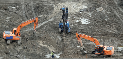 Tractors and excavators work on the construction of the foundation zero cycle