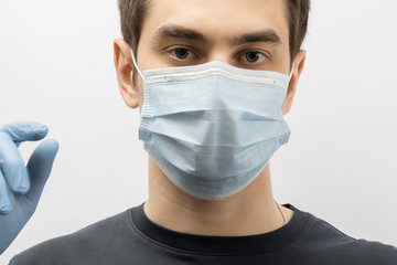 Young european man wearing mask against the corona virus and thumbs up covid 19 man wearing reusable surgical mask to prevent from virus white\grey background Corona virus pandemic funny fun