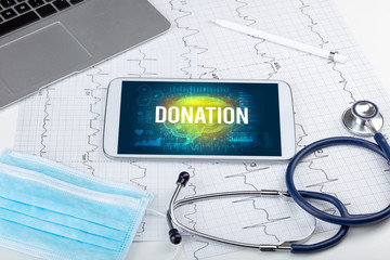 Tablet pc and medical tools with DONATION inscription, social distancing concept