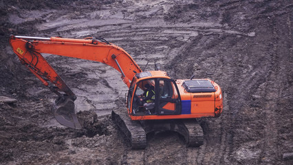Workers in the mud of a construction site at the stage of excavation; construction of a supermarket...