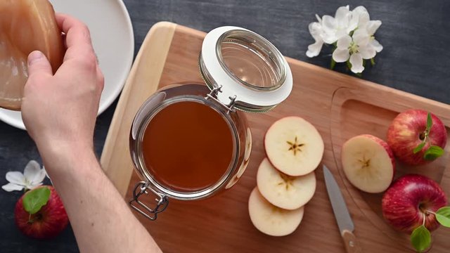 Kombucha SCOBY disk Symbiotic culture of bacteria and yeast in the hand of an unrecognizable man. Cooking healthy probiotic kombucha or apple cider drink. Dark rustic wooden table. Top view