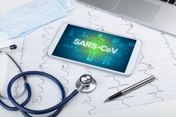 Tablet pc and doctor tools with SARS-CoV inscription, coronavirus concept