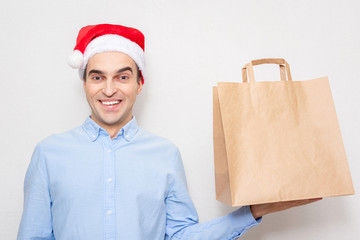 Concept of a new year. Man in Santa Claus hat with gift bag, portrait, white background, copy space