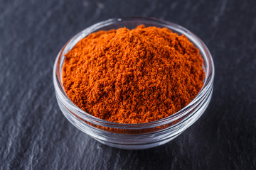 aromatic spicy chilli powder on a dark stone background