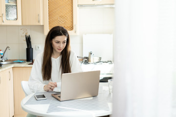 Obraz na płótnie Canvas The girl studing online with laptop in kitchen